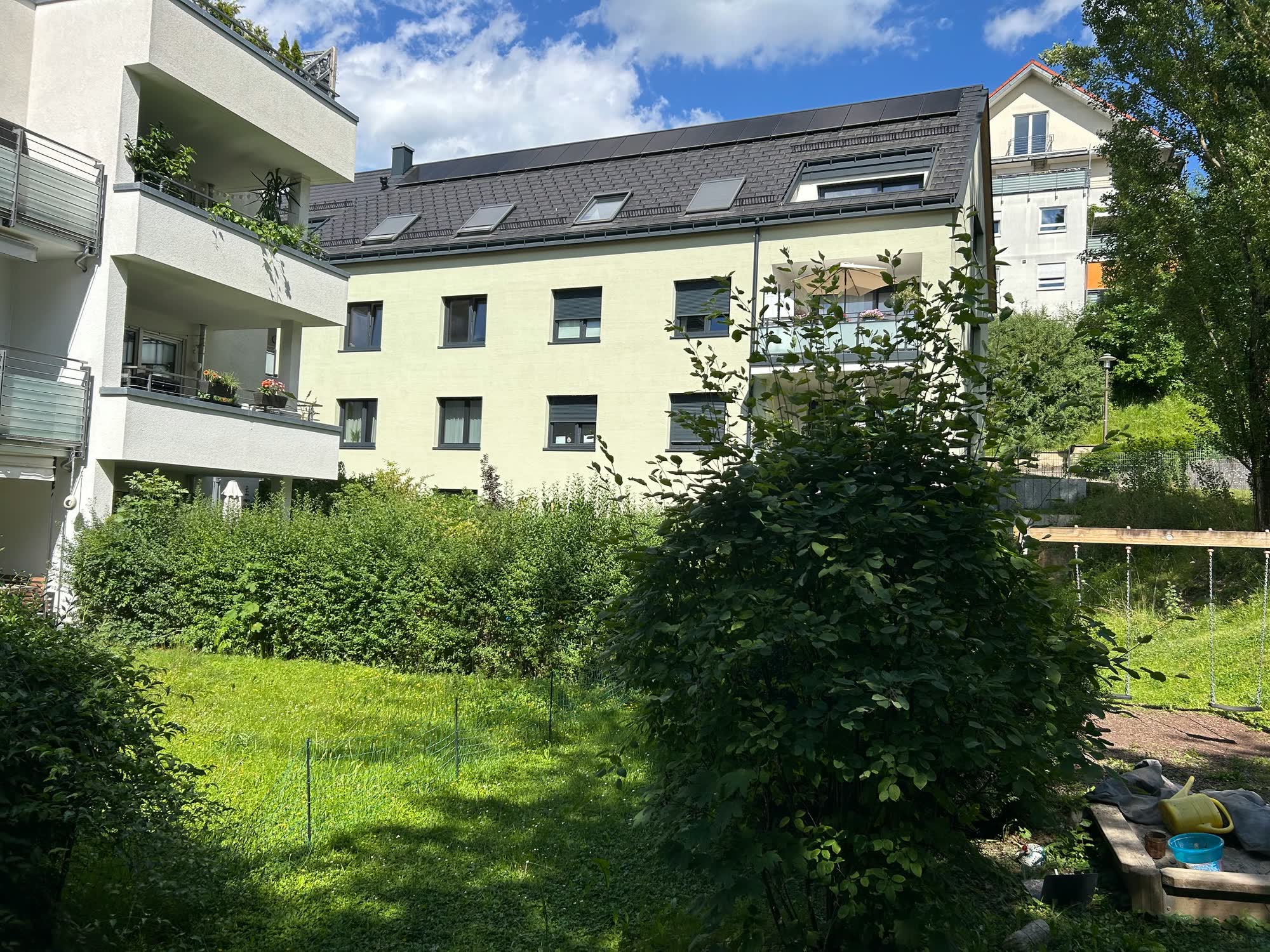 Mehrfamilienhaus mit hellgelber Fassade, Photovoltaik und Garten